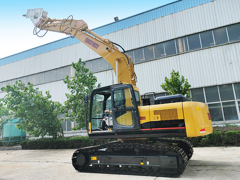 Side view of a yellow NEW SKY excavator with a hydraulic hammer attachment and raised boom, operator seated in cab, factory background. Side view of a yellow NEW SKY excavator with a hydraulic hammer attachment and raised boom, operator seated in cab, factory background.